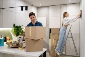 Couple unpacking moving boxes in a modern kitchen while decorating their new home.