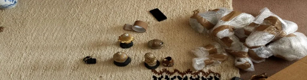 Decorative golden ornaments on a carpet with bubble-wrapped items and packing tape nearby