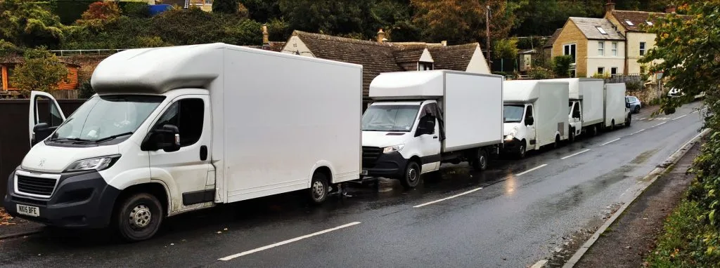 Row of white moving trucks parked along a residential street.