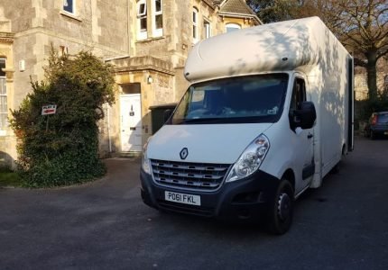 White removal van parked outside a stone residential building.