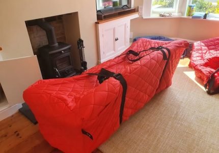 Furniture wrapped in red protective covers inside a living room.